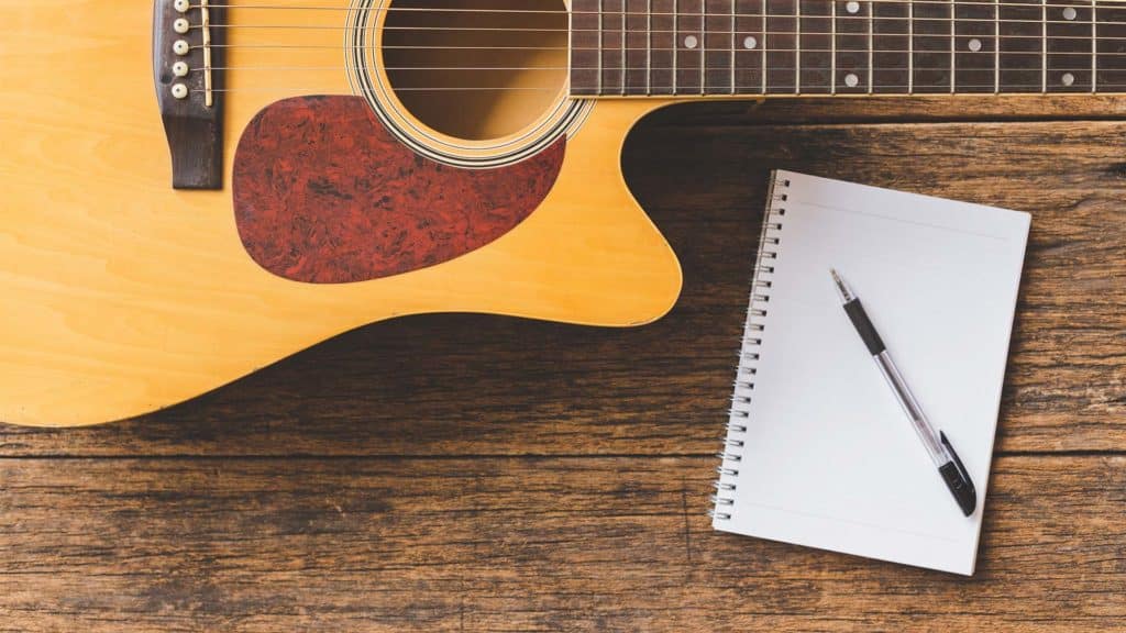 Guitar and pad of paper on wood table